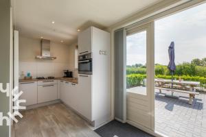 cocina con armarios blancos y vistas a un patio en Gezellige vakantiewoning met een zonnig terras, en Serooskerke