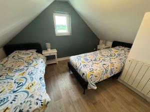a attic bedroom with two beds and a window at Charmante maison de campagne in La Hoguette
