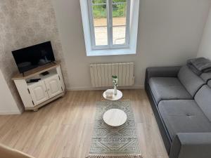 a living room with a couch and a tv at Charmante maison de campagne in La Hoguette