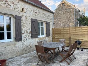 a patio with a table and chairs in front of a building at Charmante maison de campagne in La Hoguette