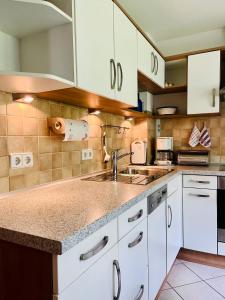 a kitchen with white cabinets and a sink at Ferienhaus Oesterle - Idyllisches Schwarzwaldhaus am Bach mit Terrasse & Balkon in Schönmünzach