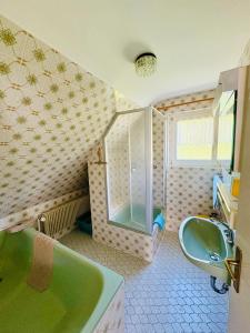 a bathroom with a green tub and a sink at Ferienhaus Oesterle - Idyllisches Schwarzwaldhaus am Bach mit Terrasse & Balkon in Schönmünzach