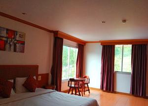 a bedroom with a bed and a table and windows at Haweli Restaurant & Guest House in Ao Nang Beach +3 photos