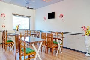 a dining room with tables and chairs and a tv at Hotel O Maurya in Pune