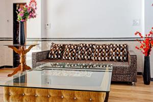 a living room with a couch and a glass table at Hotel O Maurya in Pune +26 photos