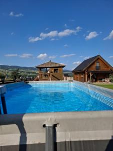 a large swimming pool with a house in the background at Domki nad jeziorem czorsztyńskim in Dębno