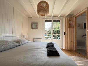 a bedroom with a bed with two towels on it at Olivia Plage, charmante maison lumineuse au calme bien équipée à 100 m plage d Asnelles, 500 m commerces, proche Arromanches et Bayeux, au coeur des plages du débarquement, jardin clos, deux belles terrasses, parking dans propriété in La Celle-sous-Gouzon