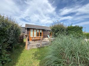 a house with a wooden deck in front of it at Olivia Plage, charmante maison lumineuse au calme bien équipée à 100 m plage d Asnelles, 500 m commerces, proche Arromanches et Bayeux, au coeur des plages du débarquement, jardin clos, deux belles terrasses, parking dans propriété in La Celle-sous-Gouzon