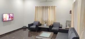 ein Wohnzimmer mit zwei Stühlen und einer Couch in der Unterkunft Footprints Villa in Panchgani