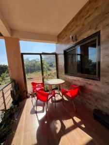 ein Zimmer mit roten Stühlen und einem Tisch auf einem Balkon in der Unterkunft Footprints Villa in Panchgani