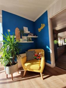 a living room with a yellow chair and a blue wall at La Maison Bisca in Biscarrosse-Plage