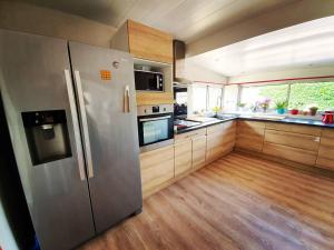 a kitchen with a stainless steel refrigerator and wooden cabinets at La Maison Bisca in Biscarrosse-Plage
