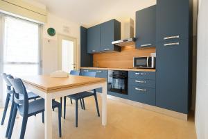 Una cocina con gabinetes azules y una mesa y sillas. en Xenia - 2 rooms apt in Corso Buenos Aires 73, en Chiavari