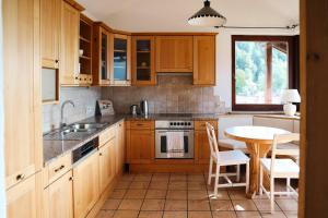 a kitchen with wooden cabinets and a table and a sink at Guesthouse am See SOL in Plescherken