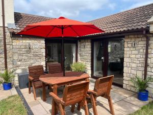 a wooden table and chairs with a red umbrella at Guest Suite King Bed in Chew Valley Bath Somerset in Chew Magna