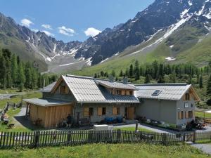 ein Haus mit einem Zaun vor einem Berg in der Unterkunft Appartements Rosmarie in Fendels