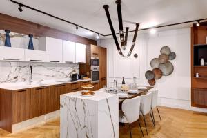 パリにあるBluestay 165 - Spacieux Appartement à Parisのキッチン(ダイニングテーブル付)、キッチン(白いキャビネット付)