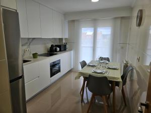 a kitchen with a table and chairs and a kitchen with white cabinets at Natalia in Allariz