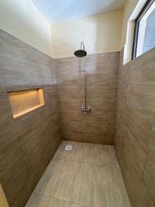 a bathroom with a shower with wooden walls at Ashnil Aruba Lodge in Tsavo