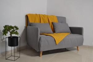 a gray couch with yellow blankets and a plant at Esion Villas in Áyios Míron