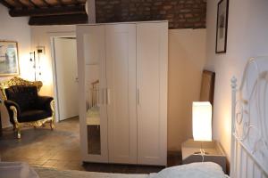 a large white wardrobe in a bedroom with a chair at LOFT CON CORTILE in Forlì +13 photos