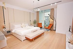 a white bedroom with a bed and a chair at Lilac Breeze 1BR - Stylish Stay with Balcony Near Saadiyat Beach & Louvre Abu Dhabi in Abu Dhabi +30 photos