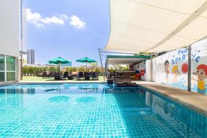 a large swimming pool with a blue tile floor at Movenpick Suriwongse Hotel Chiang Mai in Chiang Mai