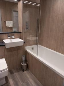 a bathroom with a sink and a tub and a toilet at Sandown Park Lodge in Esher