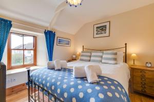 une chambre avec un grand lit avec des oreillers bleus et blancs dans l'établissement Crown Mine Cottage, à Saint Just