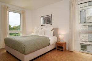 a white bedroom with a bed and two windows at Wohnkultur - Ferienhaus für 10 mit Terrasse und Garten in Wiesloch