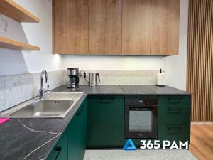 a kitchen with green cabinets and a sink at Apartament Wiatr od Morza w Let's Sea - BASEN, JACUZZI, SAUNA, SIŁOWNIA, STREFA CHILL, PARKING W CENIE - 365PAM in Gąski +33 photos