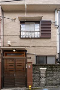 a building with a garage door and a balcony at 千住仲町House,最大8名,北千住駅徒歩8分,貸切一軒家,昔ながらの日本のお家 in Tokyo