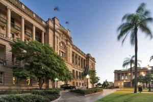a large building with a palm tree in front of it at 1Bedroom Apt in Queen's Wharf lv 62 - Skyline and City view in Brisbane