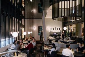 a group of people sitting at tables in a restaurant at Chrome Sonata - State Secrets & Skyline Sheets. in Brisbane