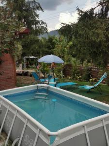 a swimming pool with an umbrella and chairs at Casa de vacanta 1001 De Nopti in Corbşori