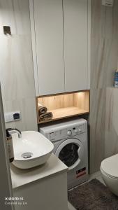 a bathroom with a washing machine and a sink at Baltic Breeze Apartamenty in Kołobrzeg
