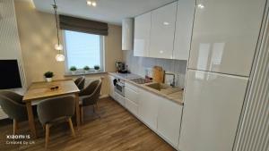a kitchen with white cabinets and a table with chairs at Baltic Breeze Apartamenty in Kołobrzeg +20 photos