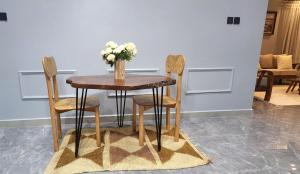 a wooden table with two chairs and a vase with flowers on it at Muyenga Tank Hill Apartments in Kampala
