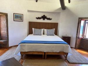 a bedroom with a large bed with a wooden headboard at In Apúlia - Moinho do Mar in Apúlia