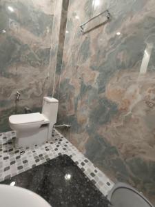 a bathroom with a toilet and a stone wall at Hotel Divaa Inn in Mathura