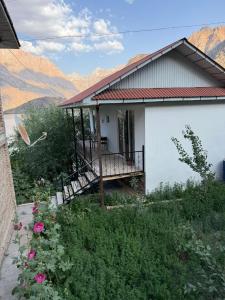 a house with a balcony and mountains in the background at ISKANDARKUL GUEST HoUSE in Kanchoch