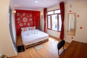 une chambre avec un lit avec un mur rouge dans l'établissement Famous House Kathmandu, à Katmandou