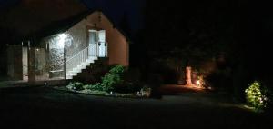 a house lit up at night with a porch and stairs at Gîte duplex Carosselle et Clarallen in Saint-Vaury