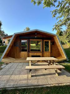 a large wooden cabin with a picnic table in front of it at ''Le Nid Alpin'' Petit cocon avec vue sur les pistes de Métabief in Métabief