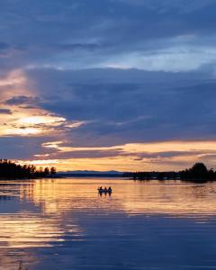 duas pessoas num barco num lago ao pôr-do-sol em Architect-Designed Cabin In Söderhamn Archipelago em Söderhamn