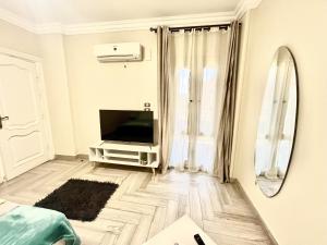 a white living room with a tv and a mirror at Rose Room in Cairo