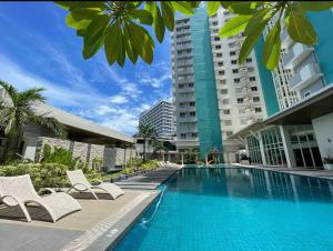 a swimming pool with white chairs and a building at Reflective Woodscape- 1 Bedroom with Balcony in Bacolod