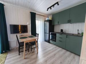 a kitchen with green cabinets and a table with chairs at Gervių takas 2 in Stotis Valiukiškes