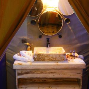 a bathroom with a sink and a mirror at Les Pyramides Luxury desert Camp in Merzouga