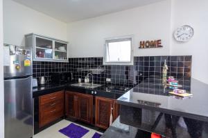 Una cocina con encimeras de azulejos negros y un refrigerador. en Franks Hill Apartment, en Phra Ae beach
